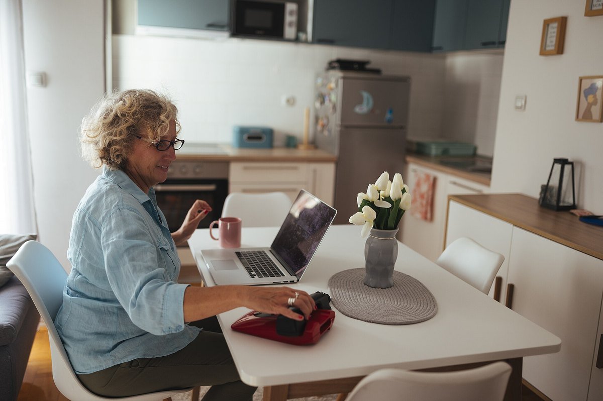 A woman working at a laptop at her kitchen table
