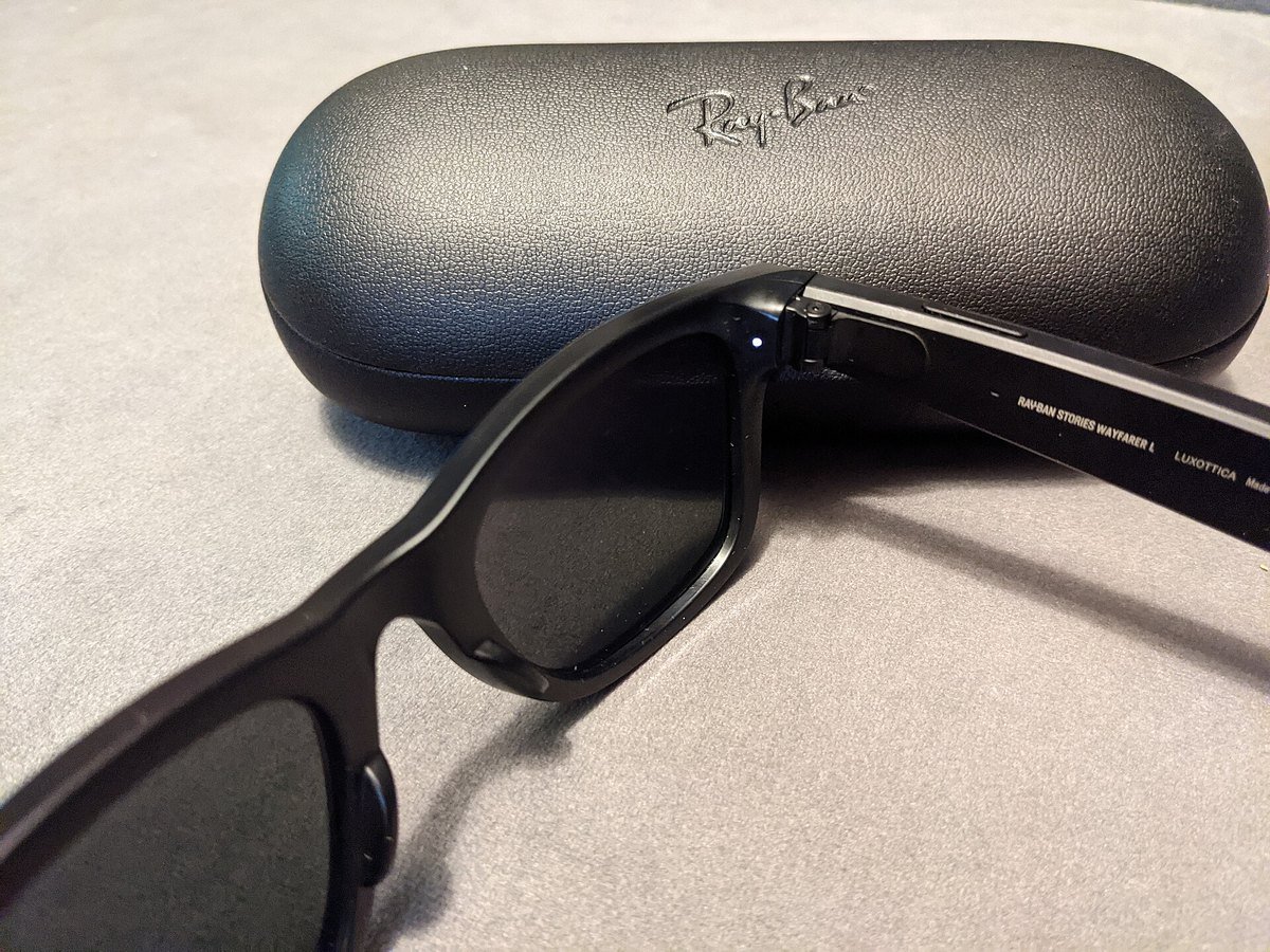 A pair of Ray-Ban smart glasses with the small white capture LED lit near the right hinge