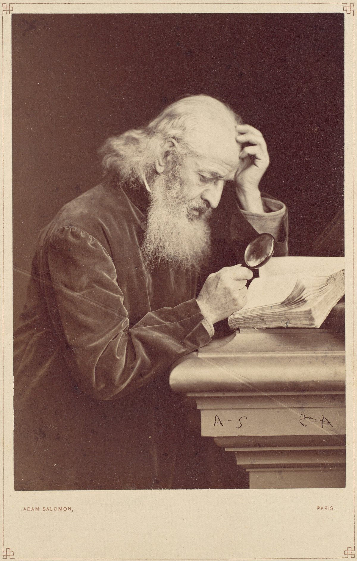 A nineteenth-century photograph of an older bearded man examining a manuscript through a magnifying glass