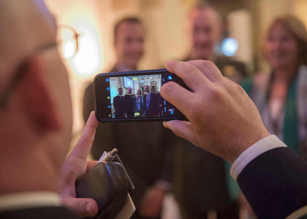 A phone screen showing a group photo with green face-detection boxes drawn around four faces