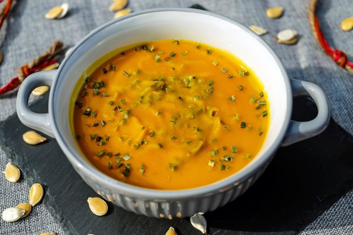 A bowl of pumpkin soup with chives and scattered squash seeds — the fall menu our example bakery wants to pre-sell
