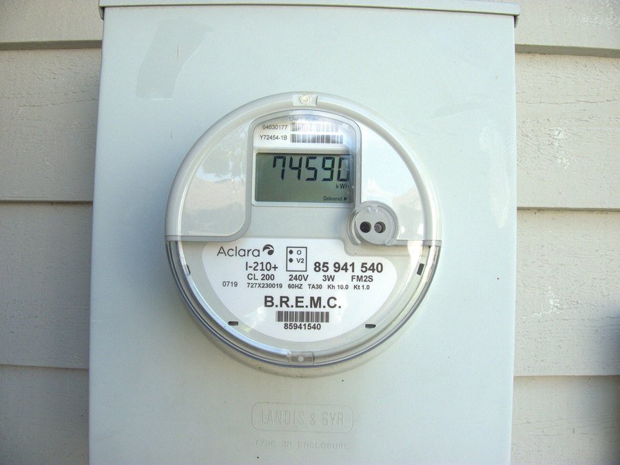 A residential smart electricity meter on the side of a house, showing a kilowatt-hour reading