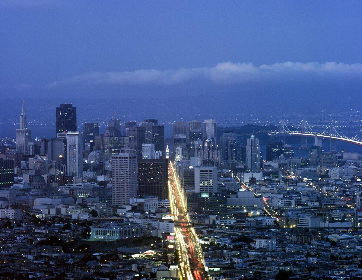 San Francisco skyline at dusk with the Bay Bridge lit in the distance