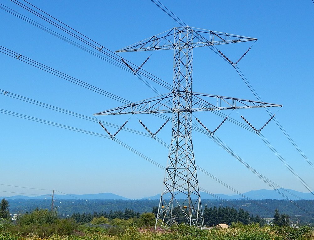 A high-voltage transmission tower and lines against a clear blue sky