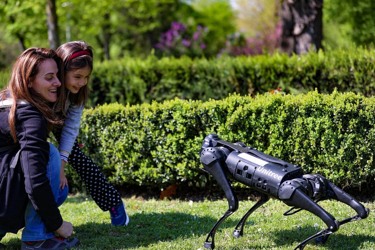 A Unitree four-legged robot dog on display at a Romanian Land Forces Day event attended by NATO personnel and members of the public.