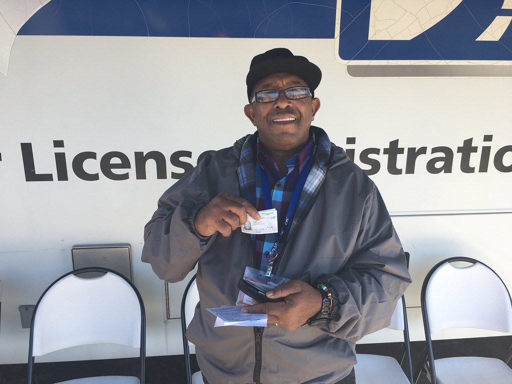A man holding a newly issued driver's license in front of a mobile License and Registration unit
