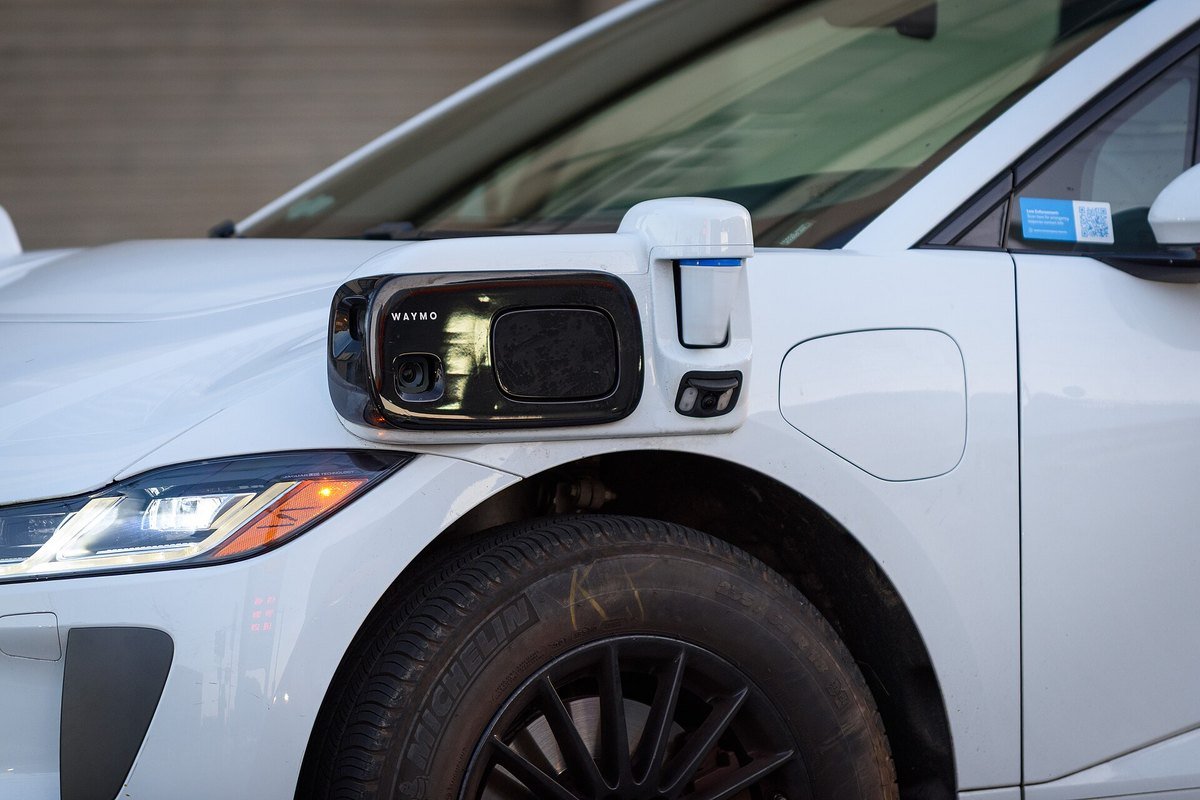 Close-up of the front sensor pod on a white Waymo Jaguar I-Pace autonomous vehicle