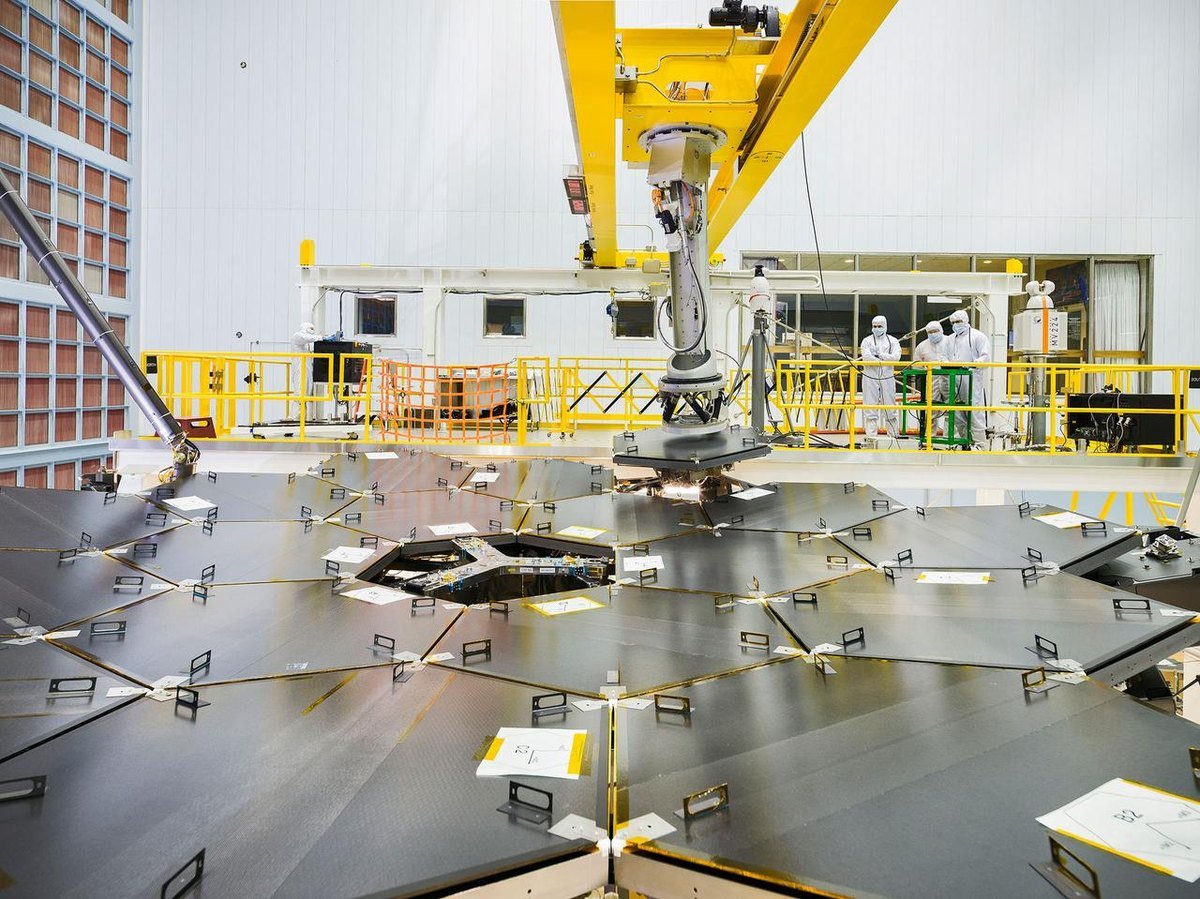 The 18 hexagonal segments of the James Webb Space Telescope primary mirror fully assembled at NASA Goddard, with engineers visible behind it