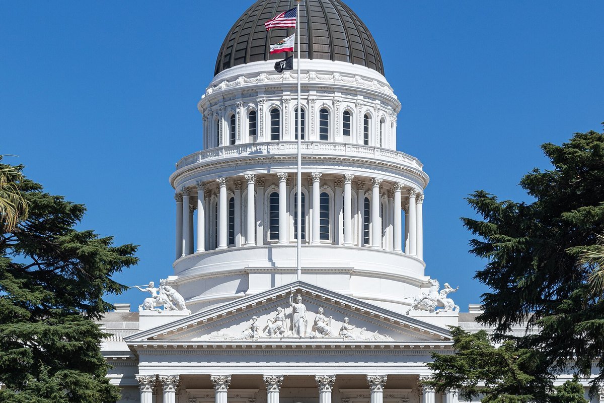 The California State Capitol in Sacramento, white dome above a row of yellow roses.