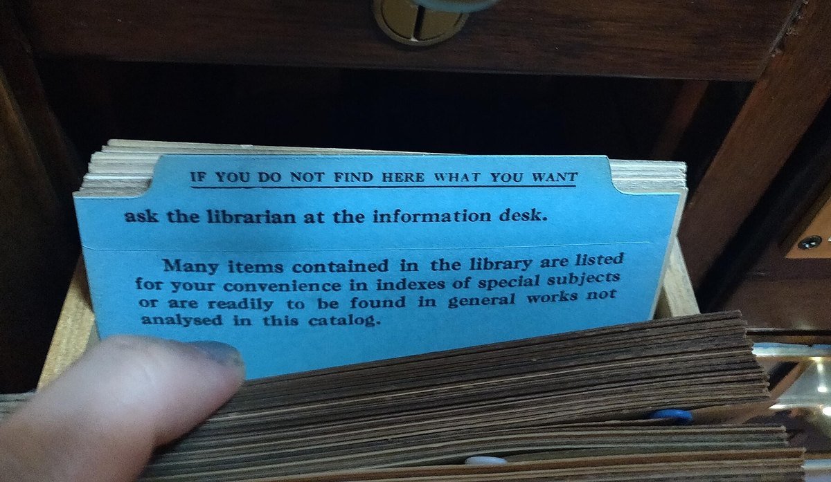 A blue guide card in a library catalog drawer reading: if you do not find here what you want, ask the librarian at the information desk.