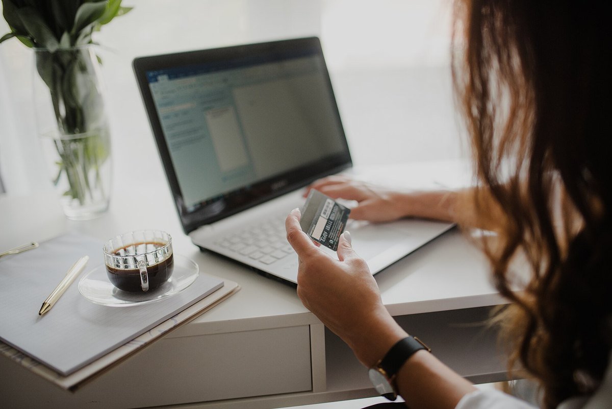 A person holding a credit card while typing on a laptop