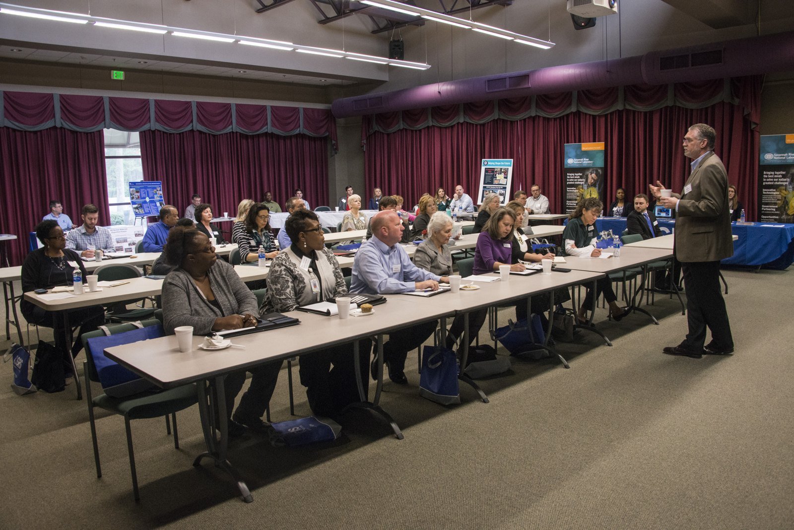 Rows of seated employers and job seekers facing each other at long tables during a reverse career fair.