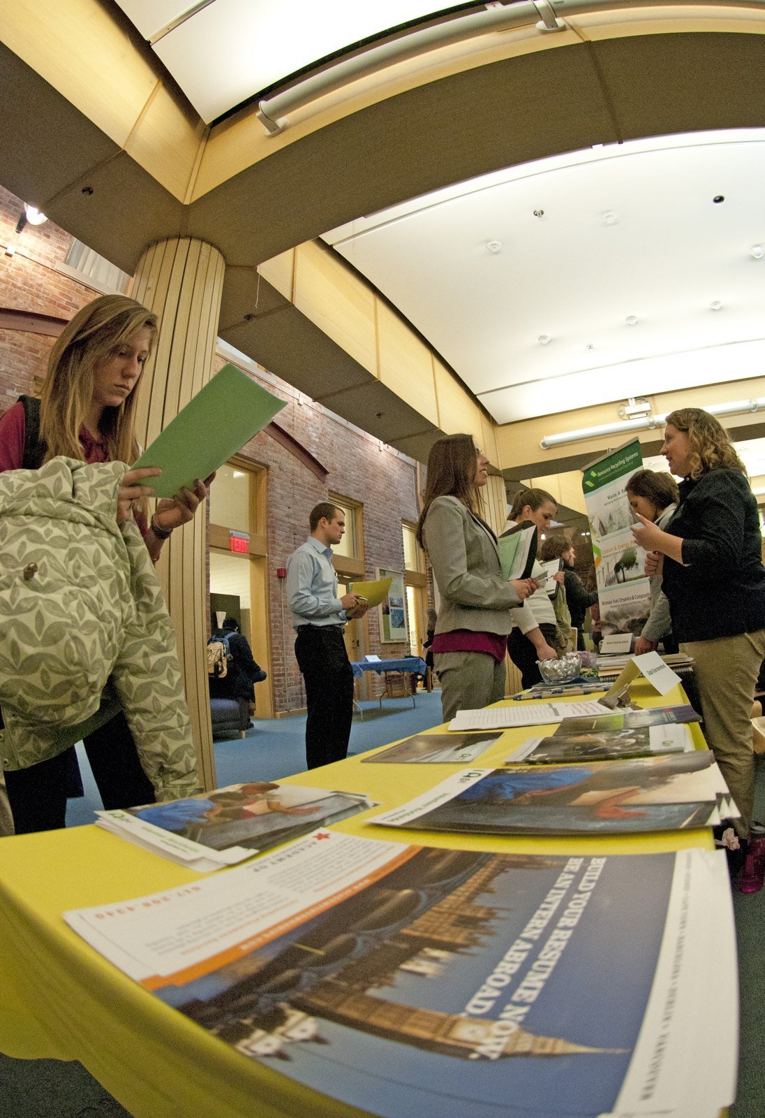 Job seekers browsing information tables along a corridor at a university career fair.