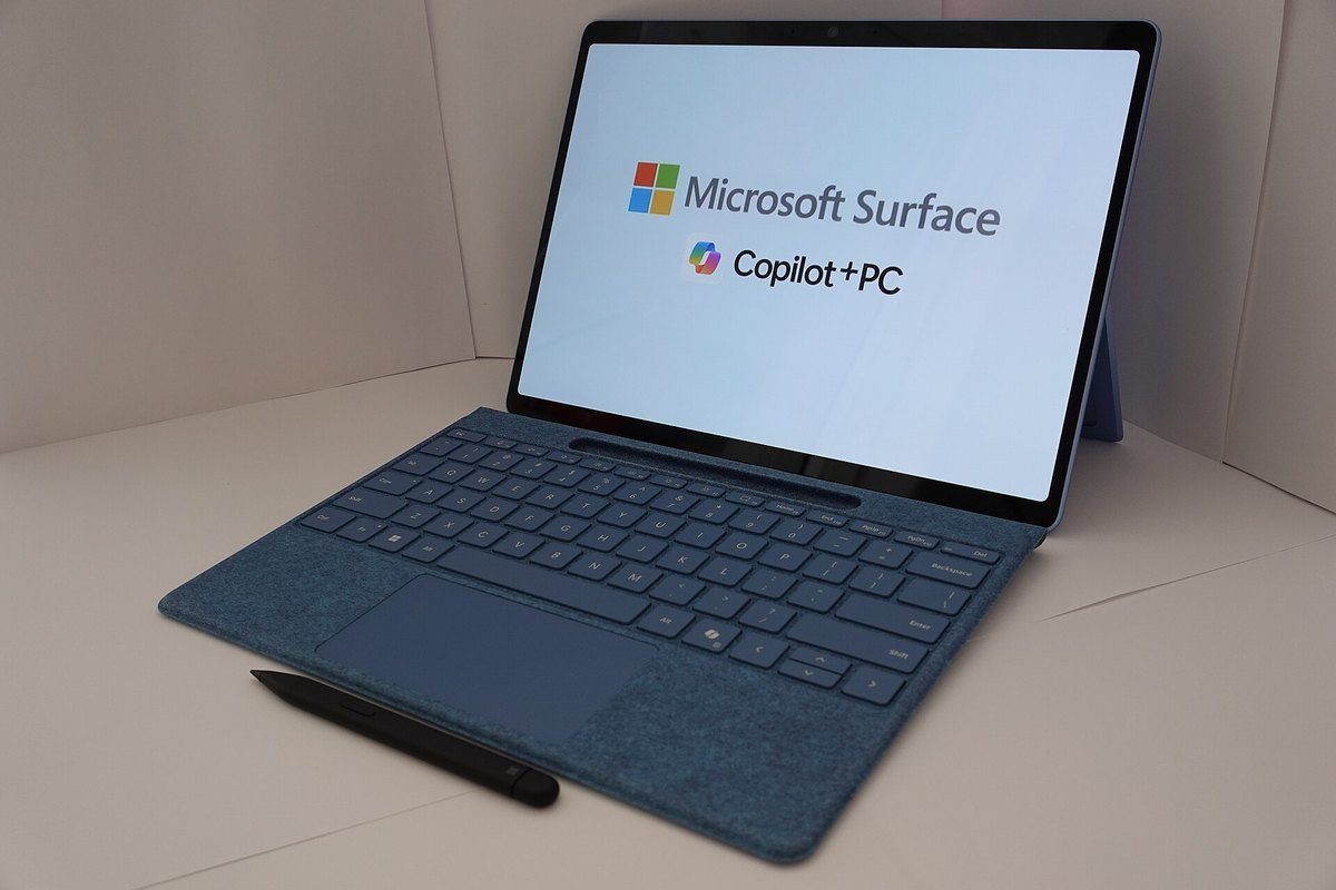 A Microsoft Surface tablet with a keyboard cover, its screen showing the words Microsoft Surface and Copilot+ PC