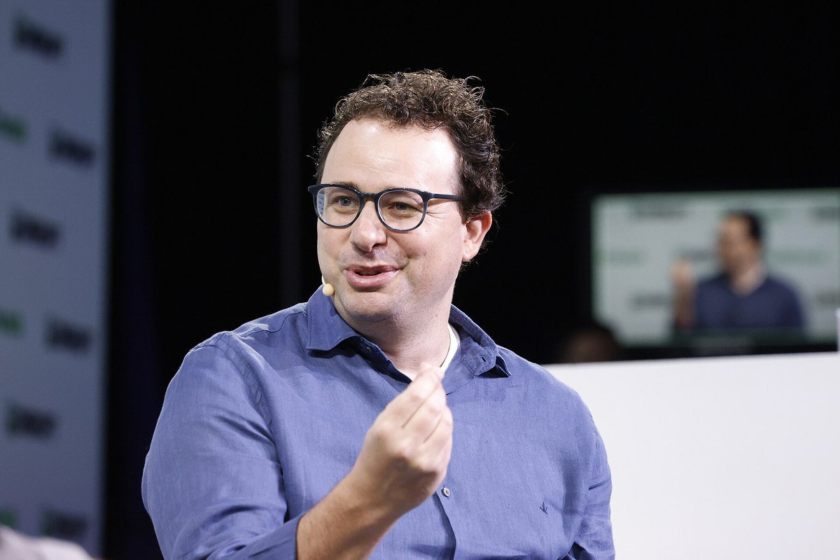 Anthropic CEO Dario Amodei in a blue shirt speaking on stage at TechCrunch Disrupt 2023.