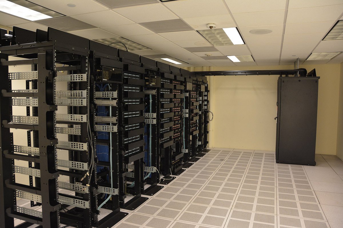 Rows of black server racks with patch panels and cabling in a data center