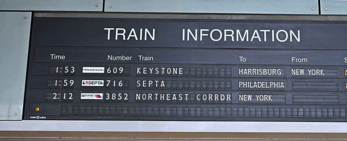 A split-flap departure board at Trenton Transit Center listing train times, destinations and track numbers.