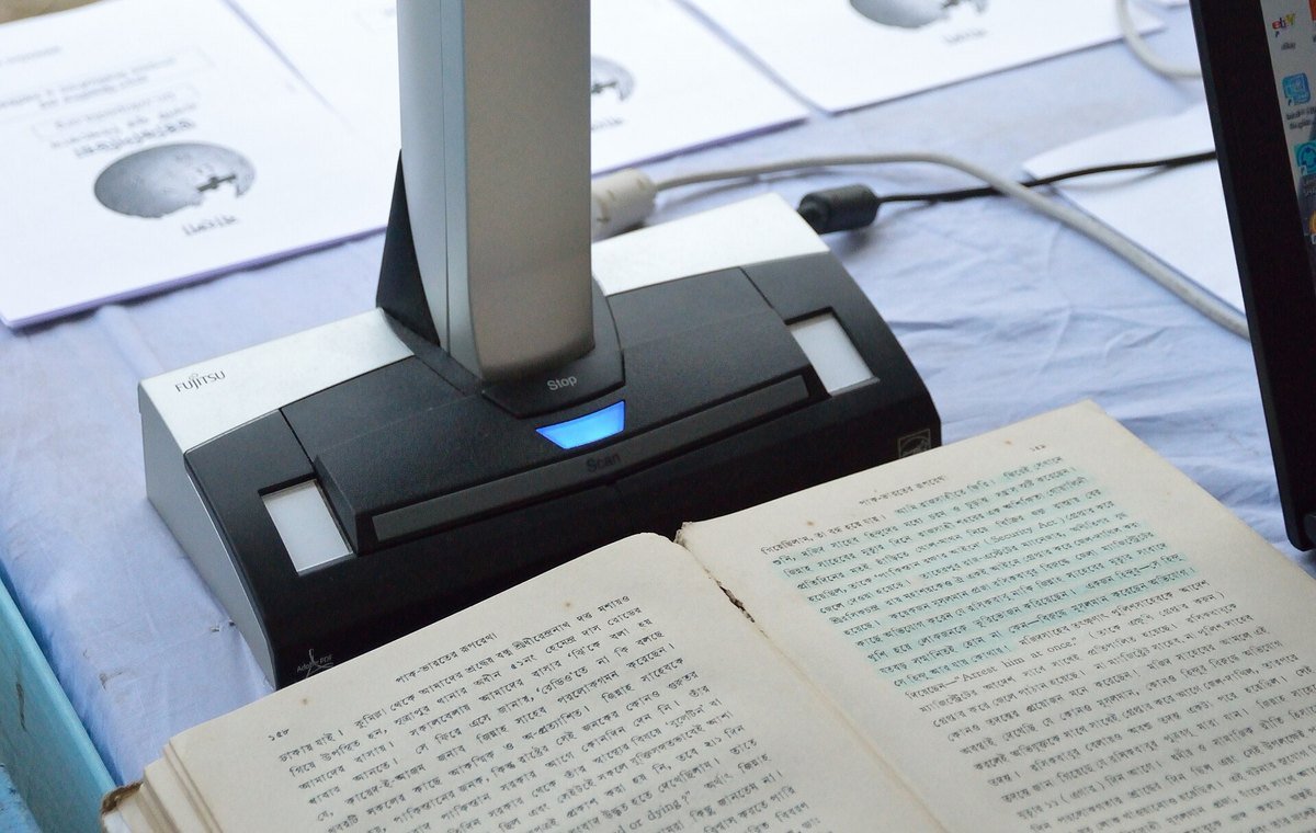 An overhead contactless document scanner photographing an open book on a table