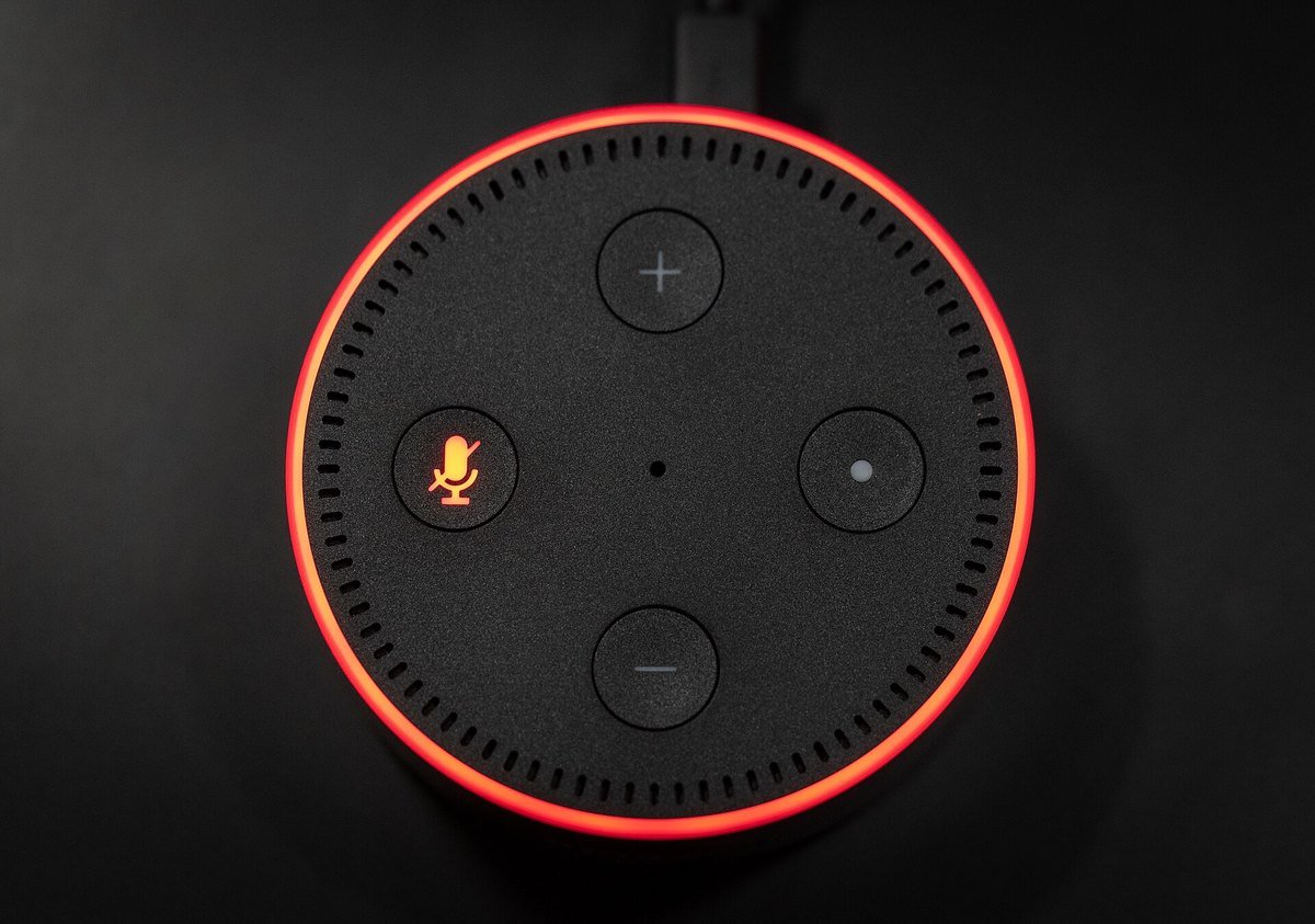An Amazon Echo Dot glowing red with the crossed-out microphone icon lit, meaning the microphone is switched off
