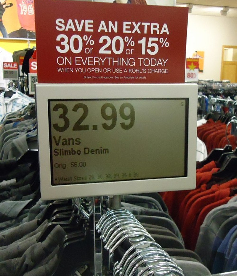 An electronic shelf display in a New Jersey store showing a marked-down price, beneath a tiered discount sign