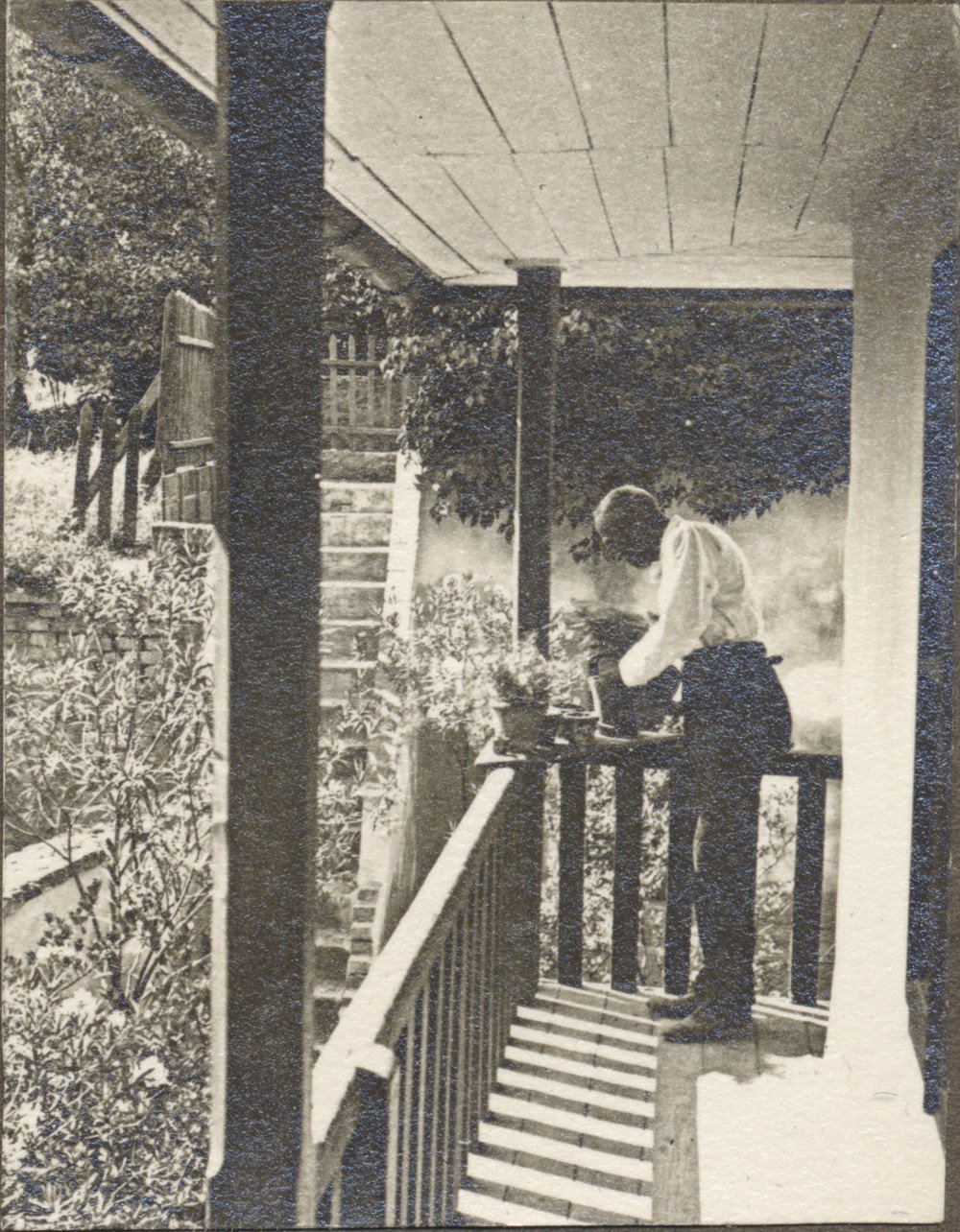 A page from an old family photo album showing a figure on a veranda.