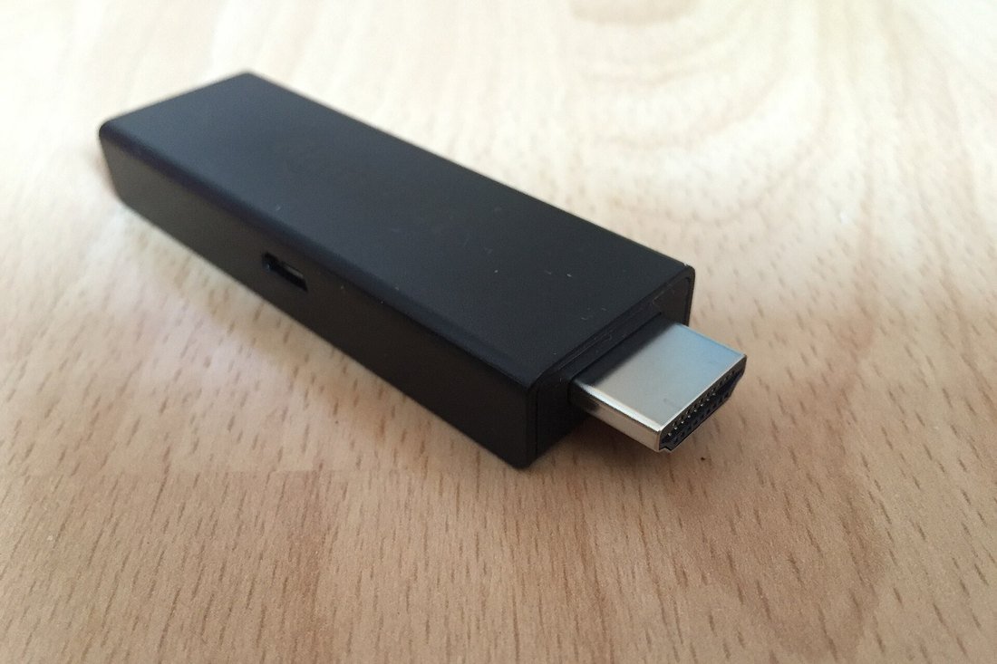 An Amazon Fire TV Stick lying on a wooden table with its HDMI connector exposed