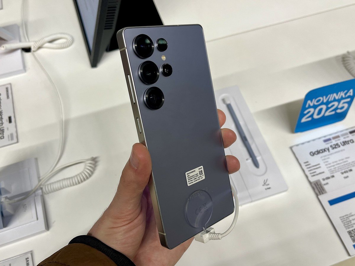 A Galaxy S25 Ultra held in one hand on a store display table.