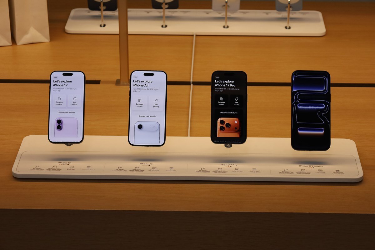 Four iPhone models on an Apple Store display table, each screen showing a See pricing button
