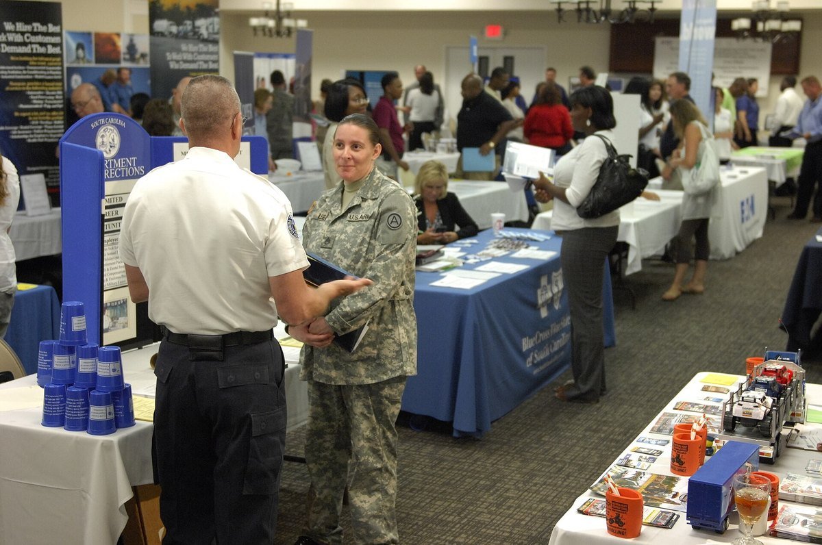 Recruiters and job seekers talking across tables at a job fair.