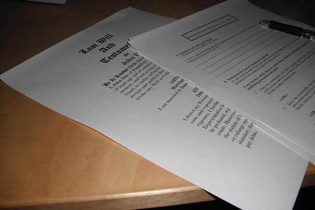 A printed last will and testament form and a health care directive lying on a desk with a pen