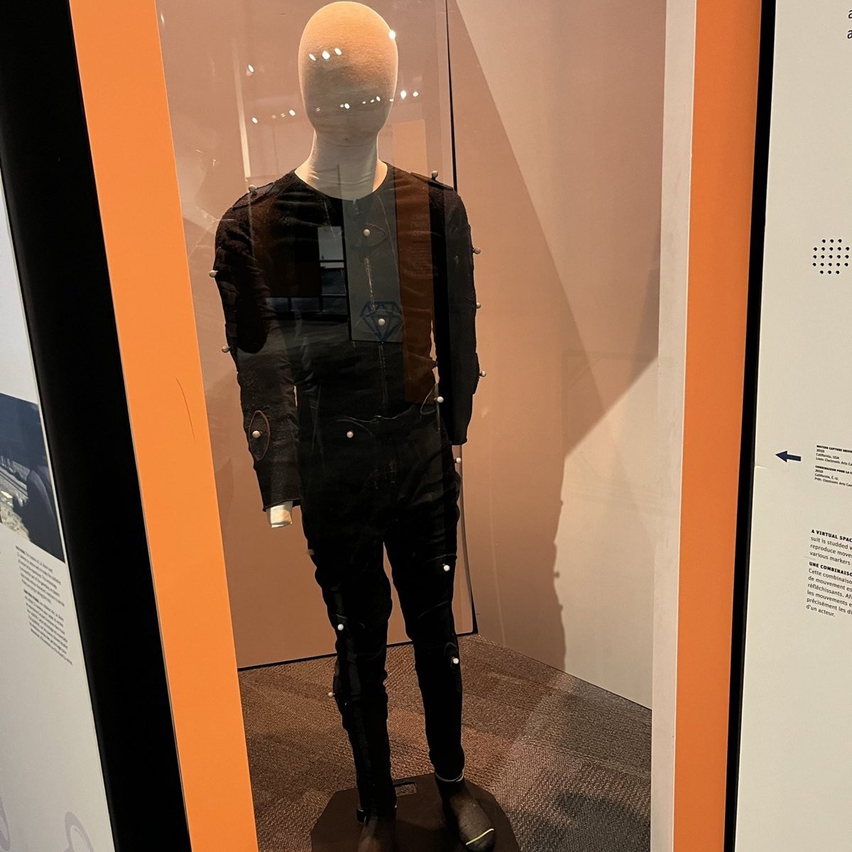 A black motion capture suit with tracking markers displayed on a mannequin