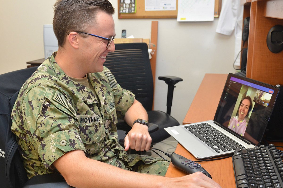 A sailor speaks with a clinician over a video call at a Navy medical facility