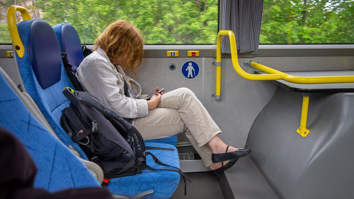 A woman sitting on a bus looking at her phone.