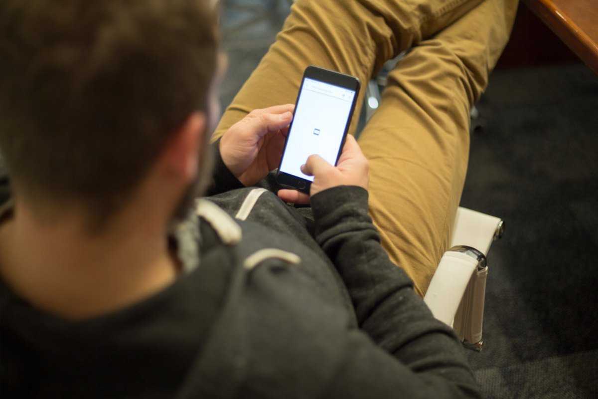 Over-the-shoulder view of a man reading his phone screen.