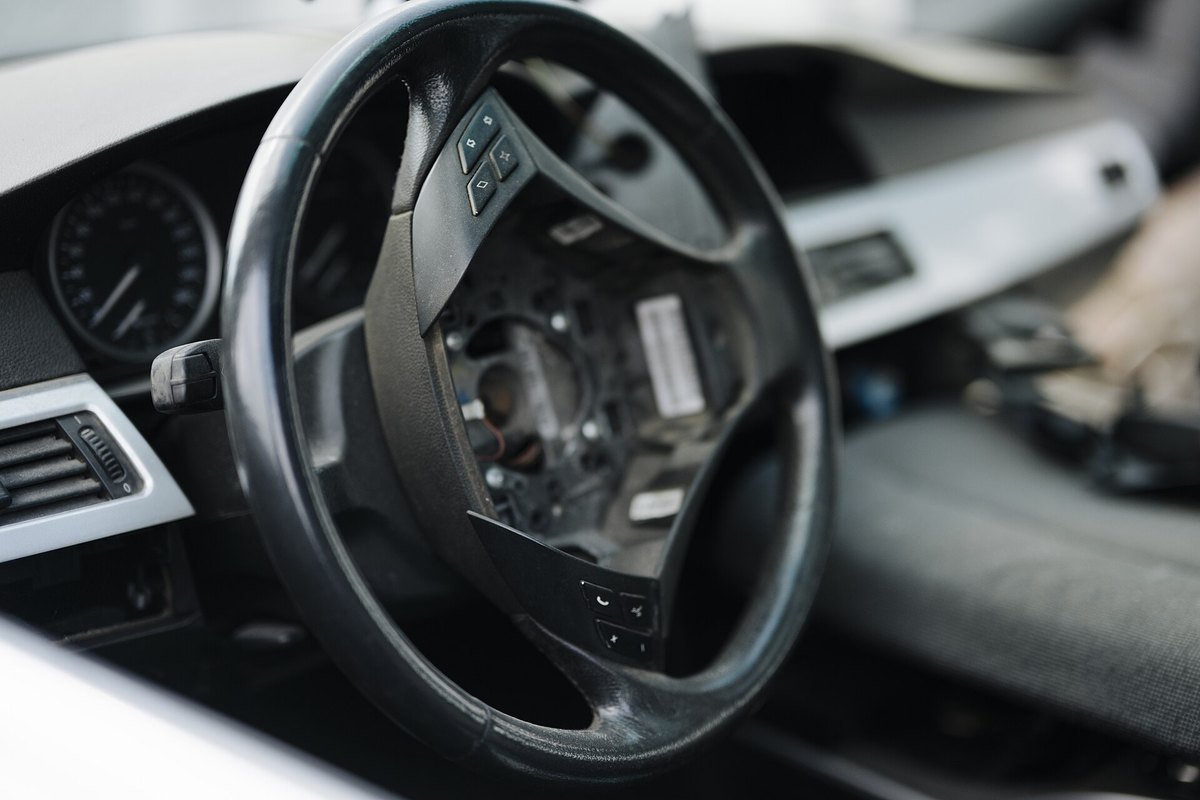 A steering wheel with its cover removed, showing the switchgear and wiring underneath