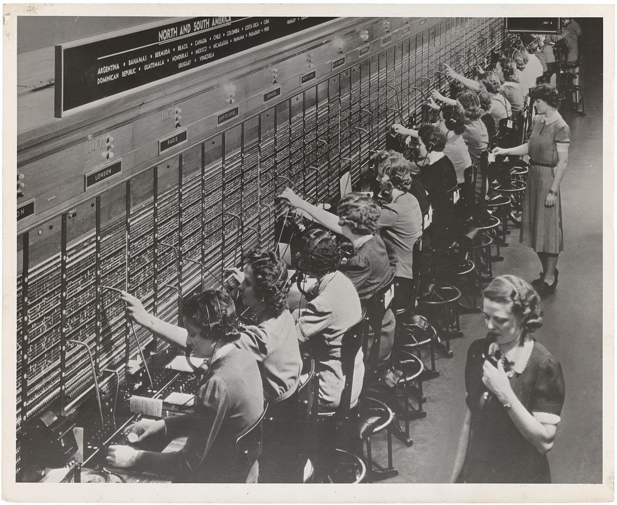 Rows of women operators at a Bell System international telephone switchboard, connecting calls by hand with patch cords
