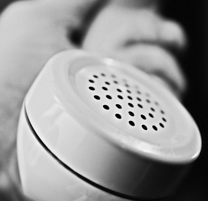 A telephone handset held out with the mouthpiece toward the viewer