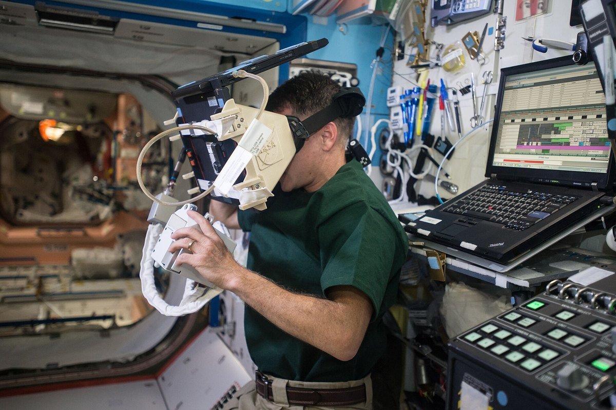 Astronaut wearing a virtual reality headset and holding a hand controller in a space station lab