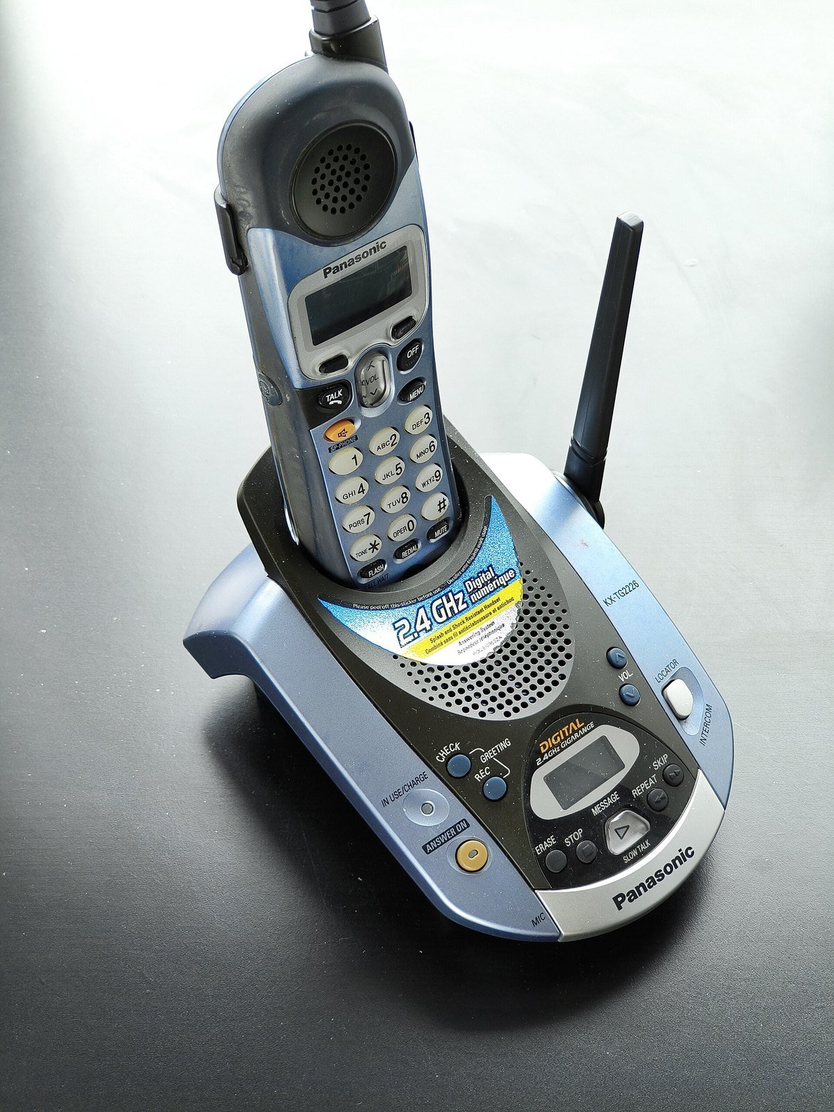A silver and blue Panasonic cordless phone standing in its base, which has a built-in answering machine