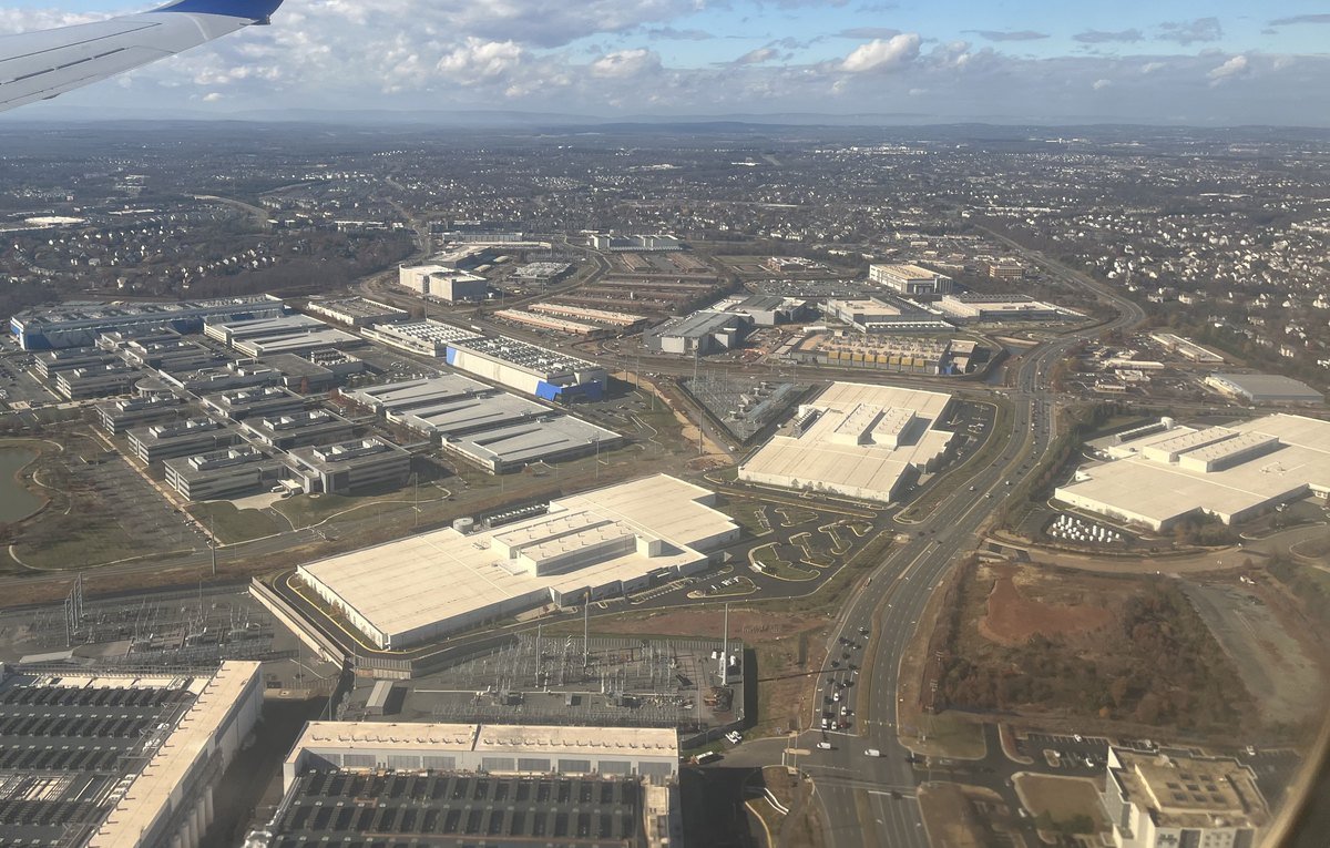 Aerial view from a plane of dozens of large flat-roofed data center buildings spread among roads, parking lots and housing developments near Ashburn in Loudoun County, Virginia.
