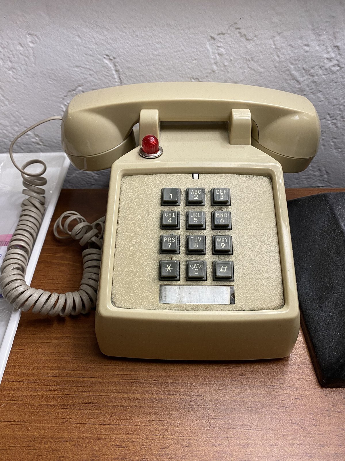 A beige desk telephone with a red message light