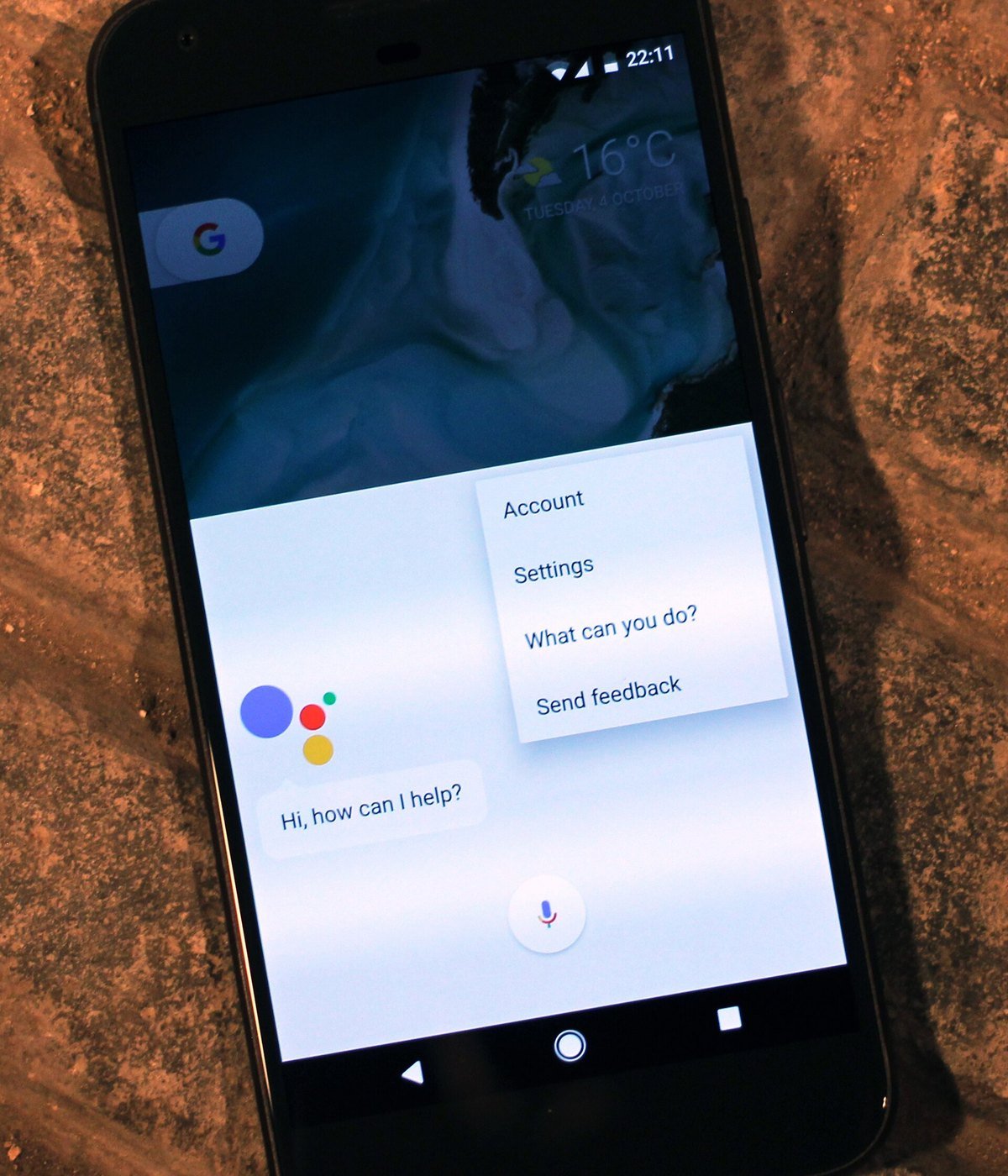 A Google Pixel XL phone showing the Google Assistant panel with the words Hi, how can I help