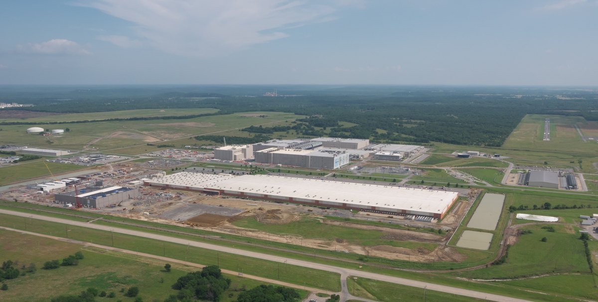 Aerial view of a long, low Google data center building on flat farmland outside Pryor, Oklahoma, with construction areas around it.