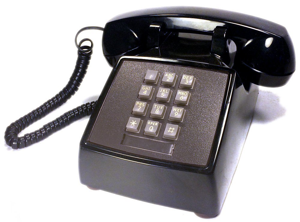 A black push-button desk telephone with a coiled cord, made by Western Electric for AT&T