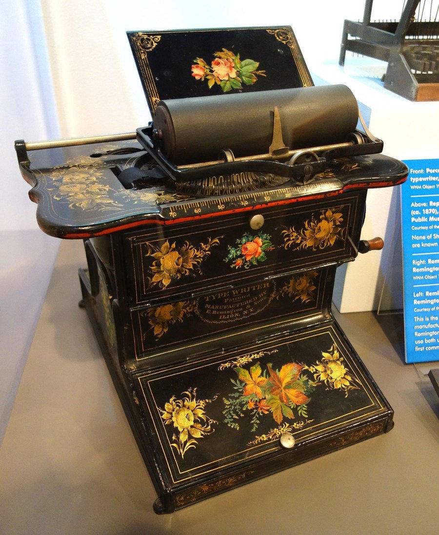 A Remington No. 1 typewriter from the 1870s, decorated with painted flowers, in a museum case