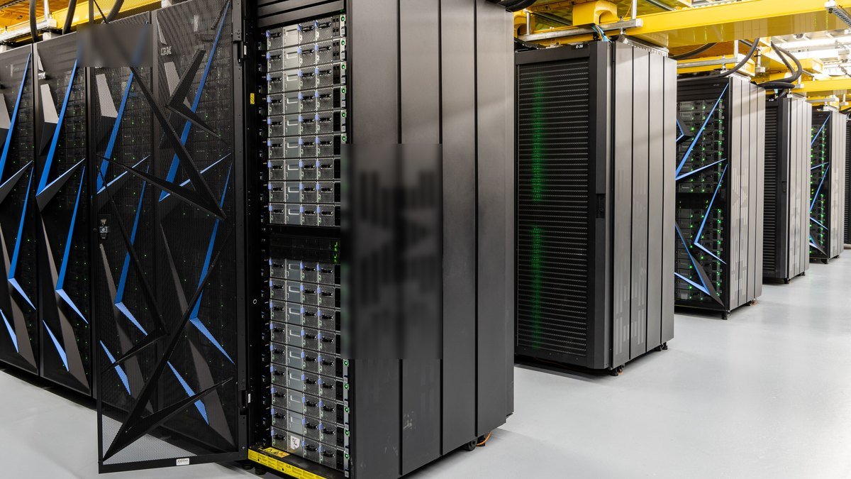 Rows of tall black supercomputer cabinets with blue accents in a bright data hall, one cabinet door open to show stacked GPU server trays, at Oak Ridge National Laboratory.