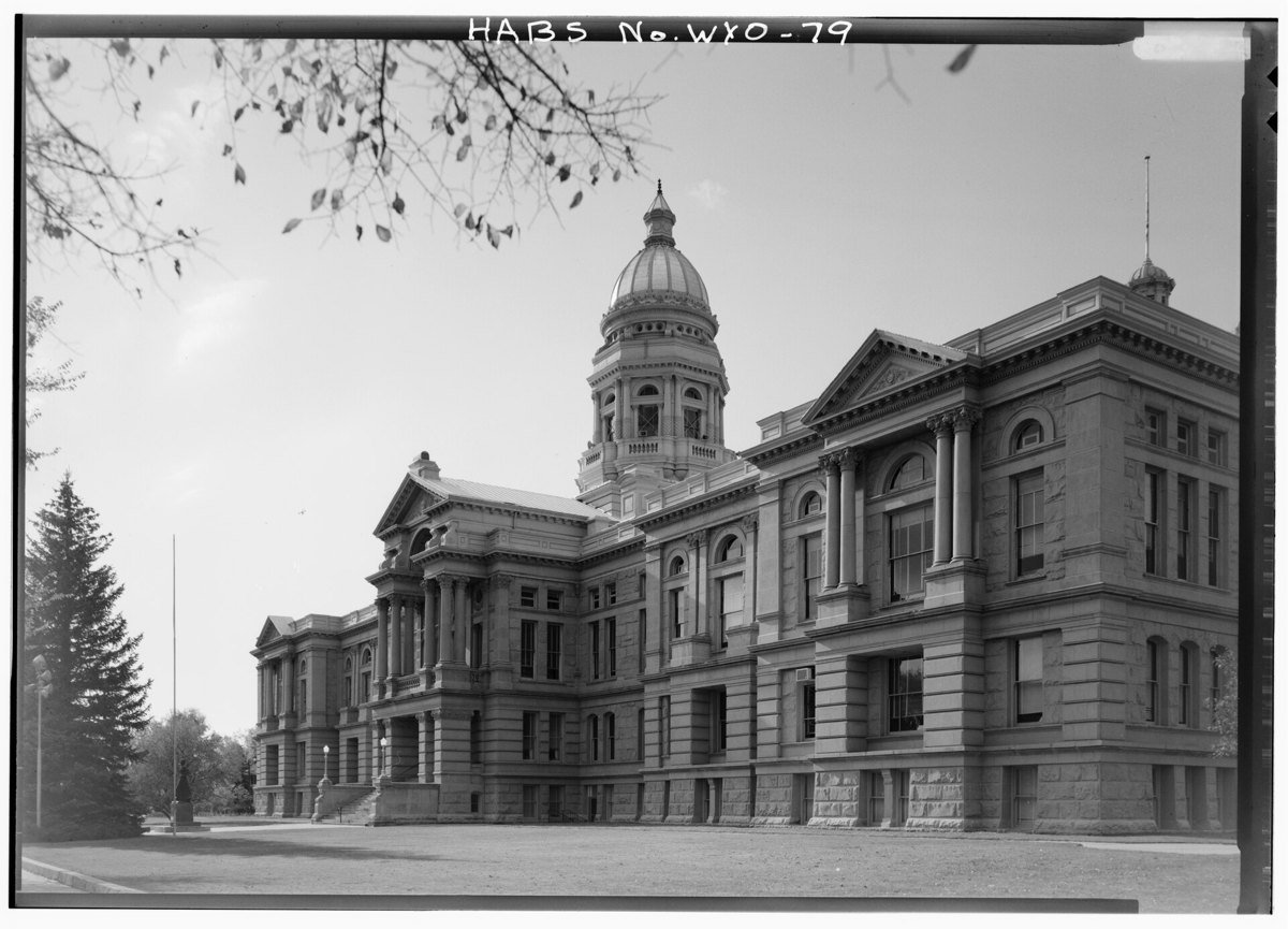 Black and white photograph of the Wyoming State Capitol in Cheyenne, a stone building with a central dome, seen from the southeast across a lawn.